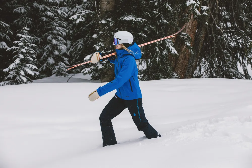 Skiers climbing snowy mountain with skis and poles in winter.