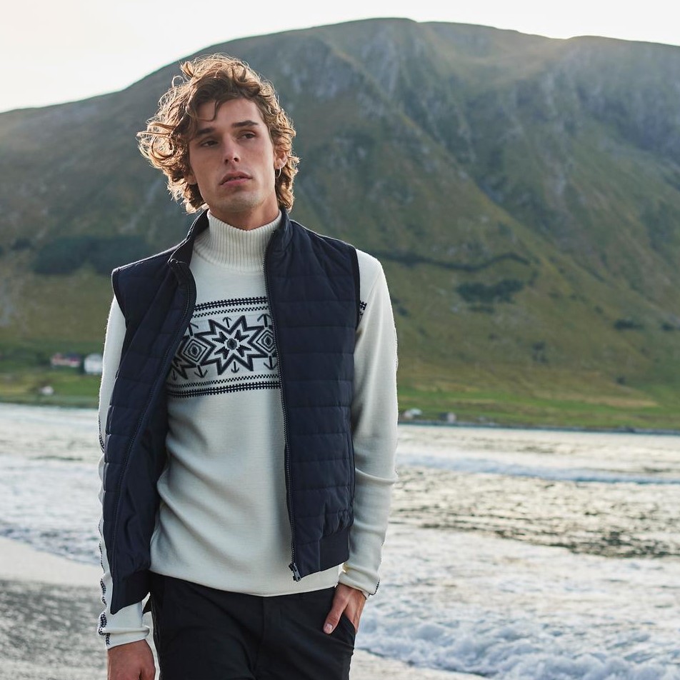 A man wearing a vest for a long walk on the beach in the cold.