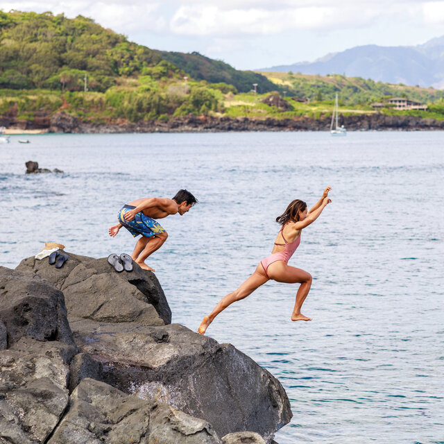 Two people enjoying the summer and jumping into water.