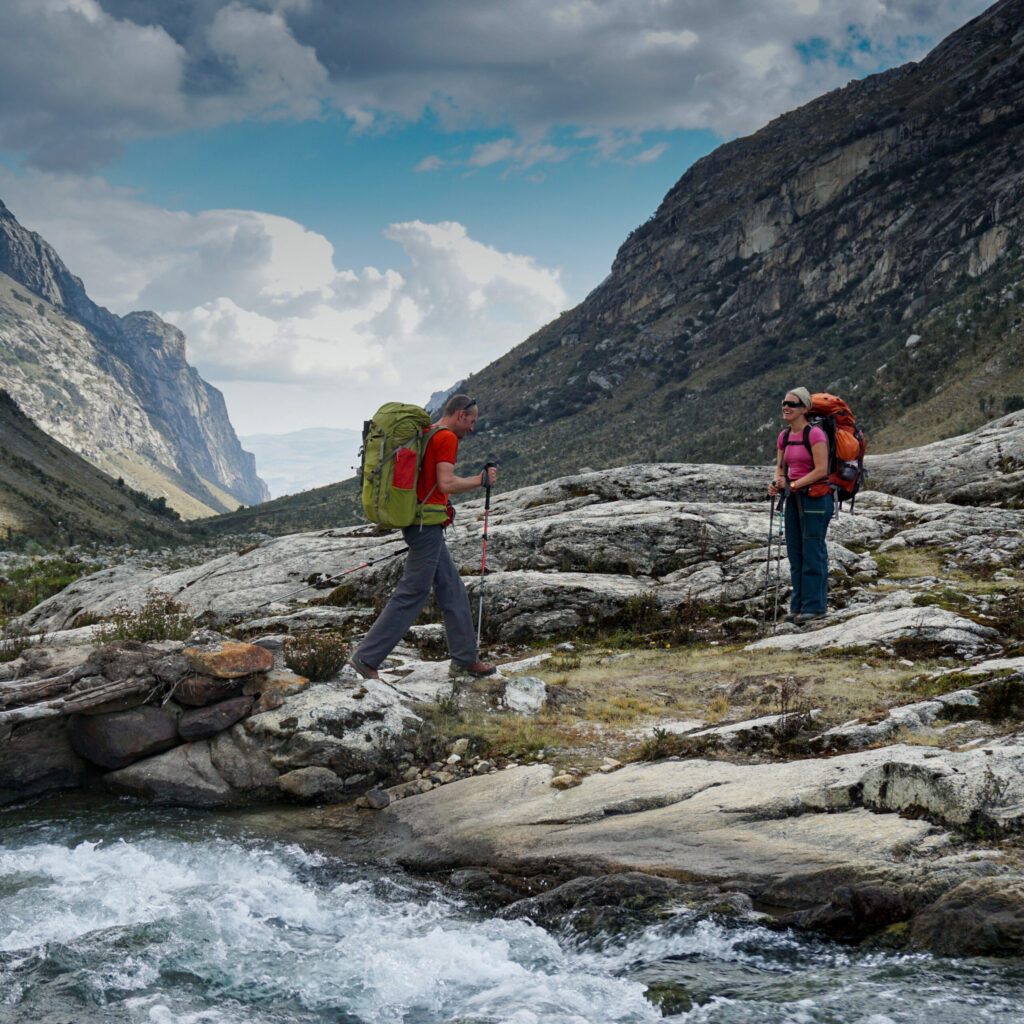 A couple trekking through the Andes after cross a stream.