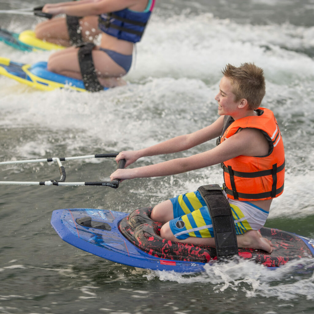 A smiling boy on a recreational kneeboard.