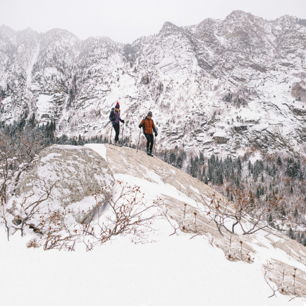 Two hikers on a winter hiking trip going down a hill on a winter mountain landscape.