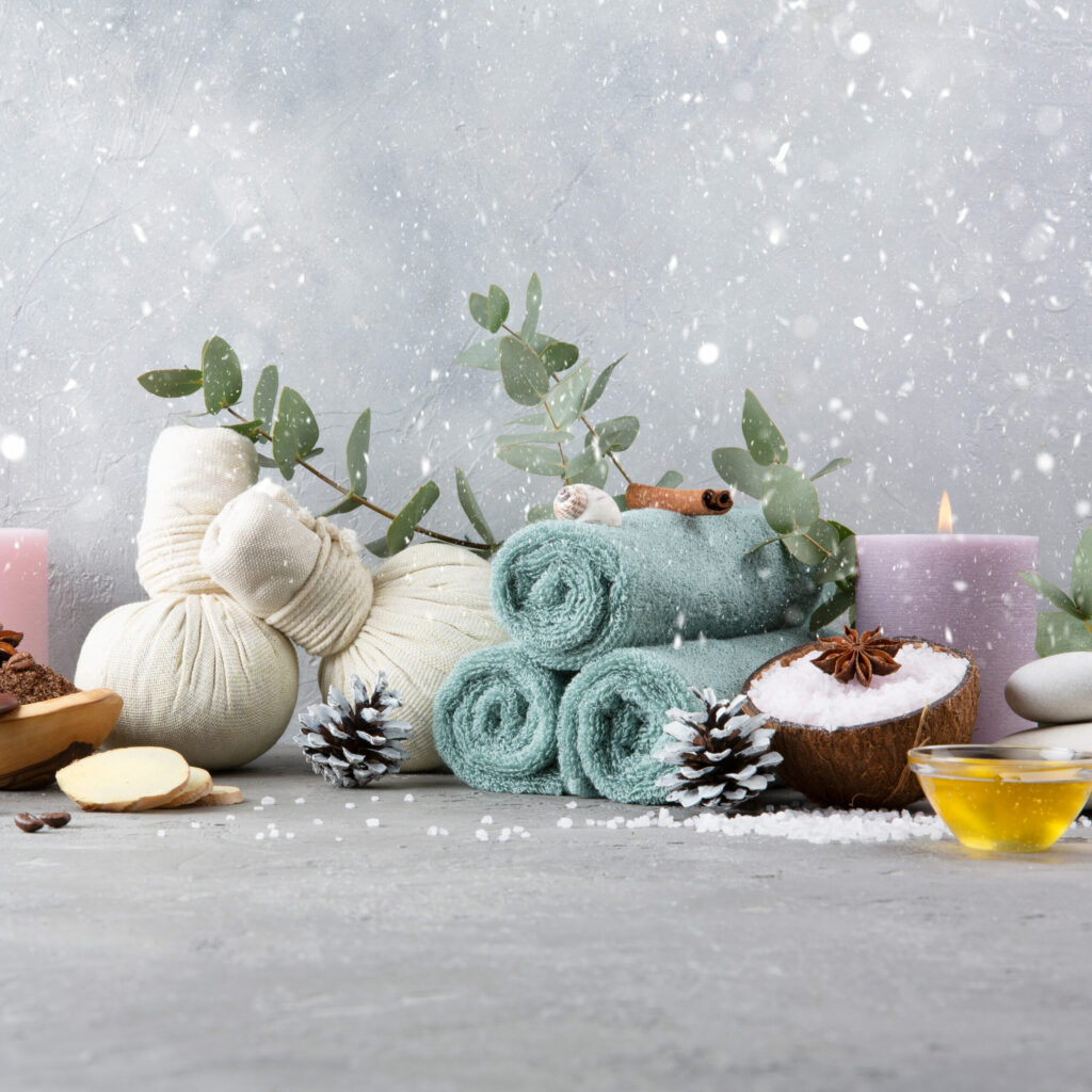 A winter spa arrangement that includes bath salts, towels, cinnamon, and massage oils.