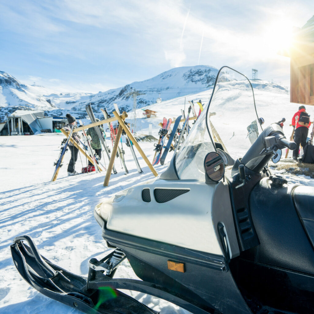 A snowmobile parked next to a mountain resort.