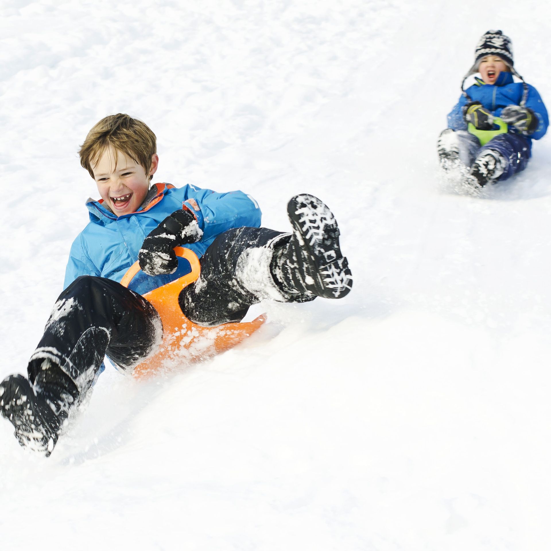 Two children sledding down a hill.