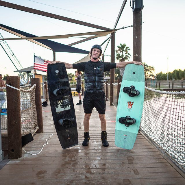 Wakeboarder Graeme Burress holding up two Hyperlite Wakeboards.