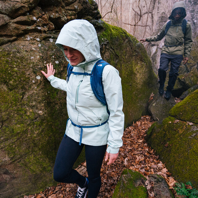 Hiking through a rainy and rocky area with The North Face Gear and a backpack with the sternum strap attached.