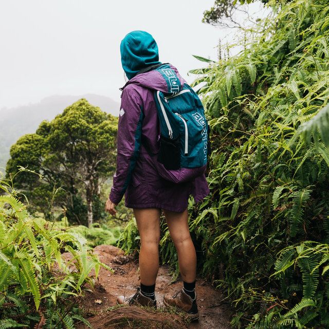 A backpacker trekking through a wet jungle path.