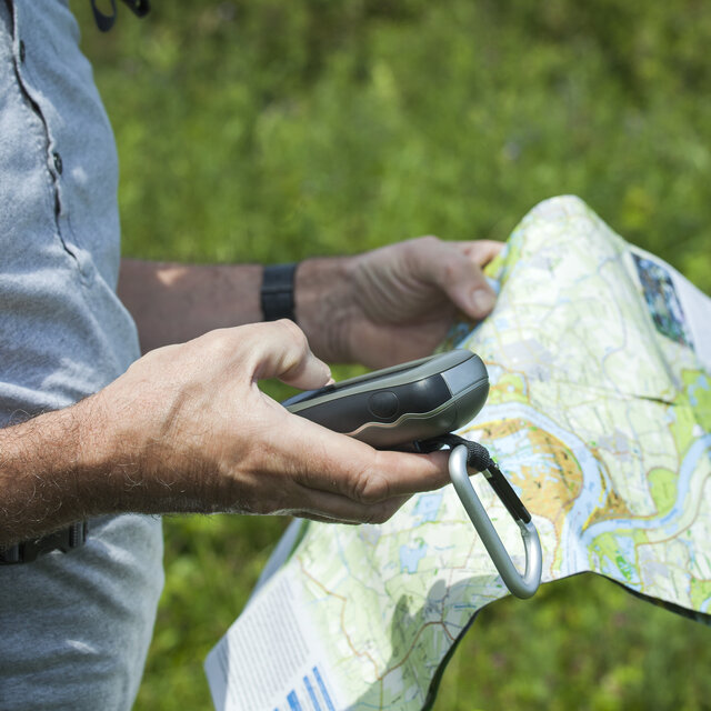 Man with gps in hand and map in other hand during a hike