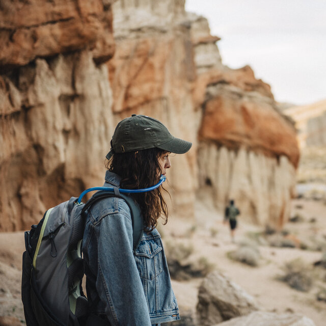 A woman hiker drinking water from her Camelbak water reservoir.
