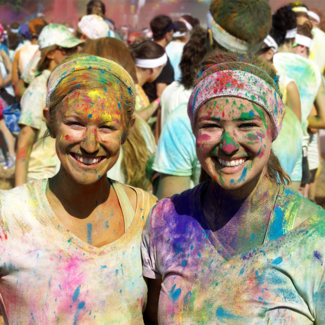 Two runners covered in colored paint after completing a fun run.