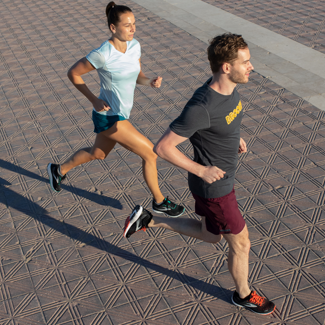 Two runners on pavement in a plaza.