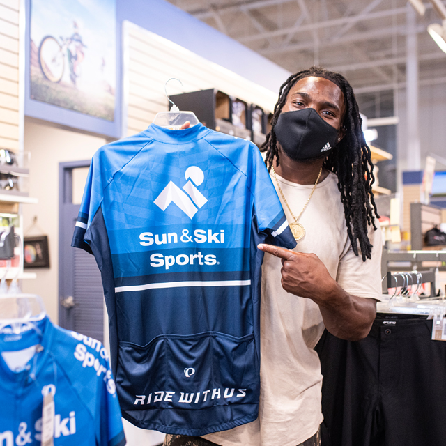 Jaylon Smith holding up a Sun & Ski Sports bike jersey.