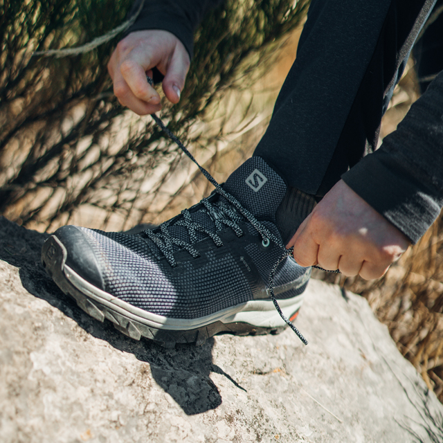 A runner tying the laces on a Solomon shoe.
