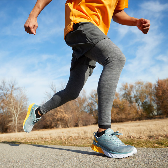 A runner with Hoka running shoes on a paved trail.