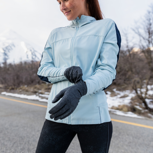 Woman pulling on cold-weather gloves.