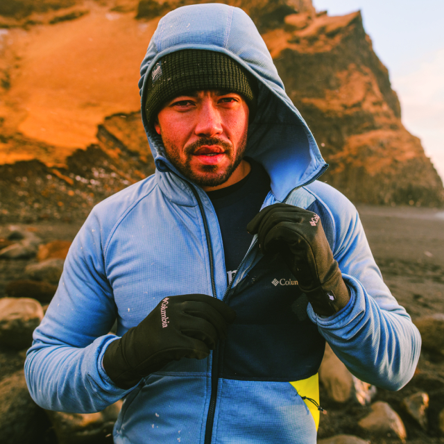 Man with cold weather gear zipping up a jacket.