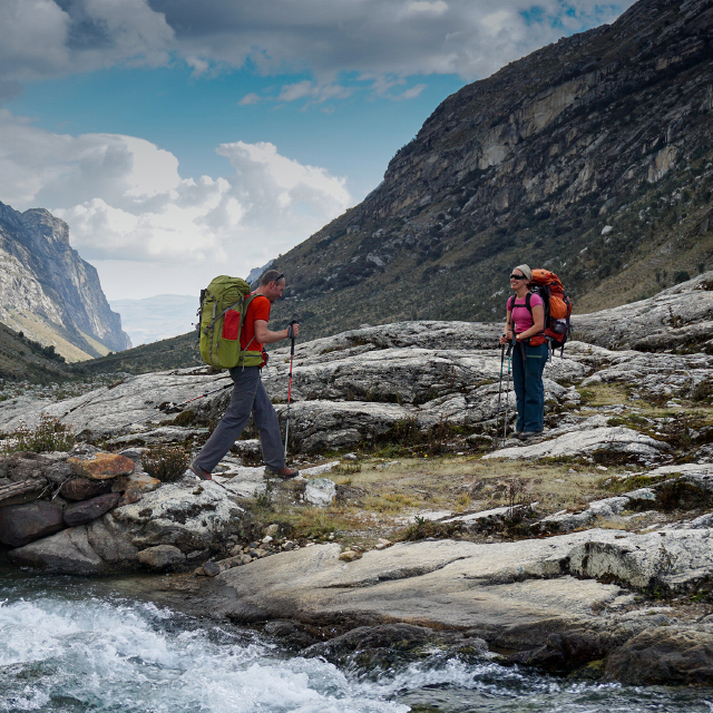 Backpackers with trekking poles exploring a vast, rocky valley.