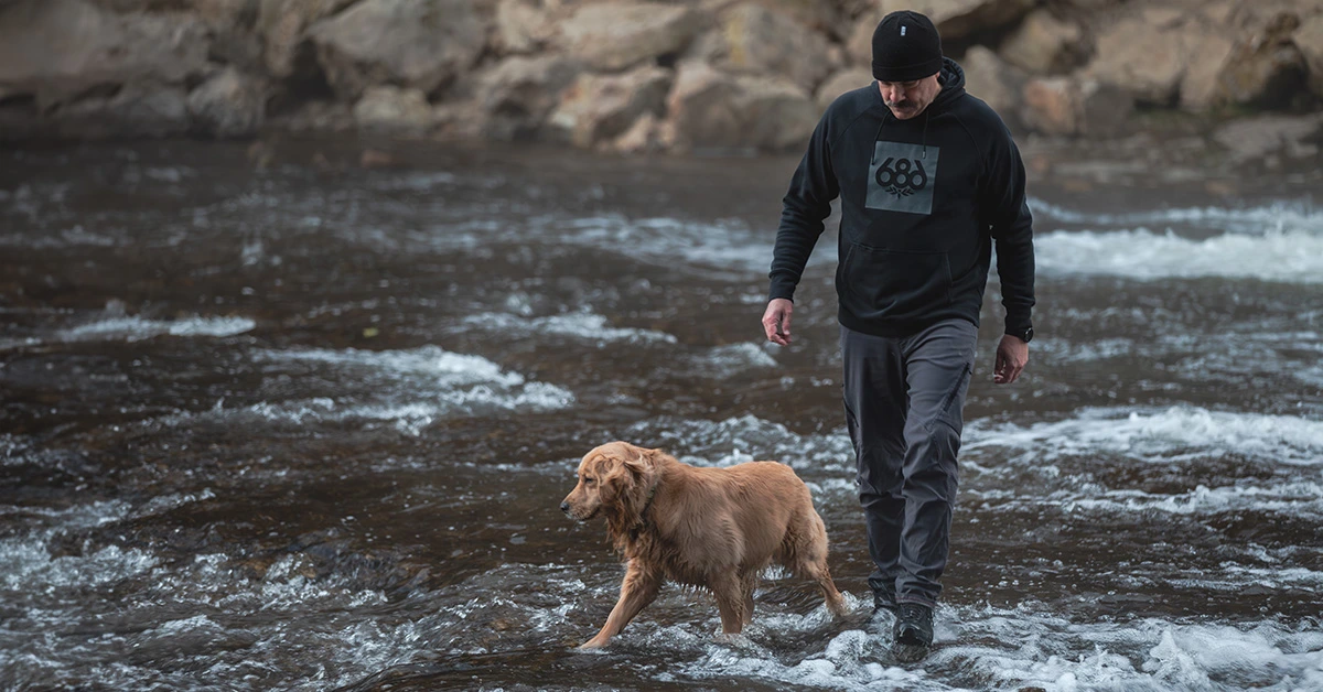 man walking in creek with dog