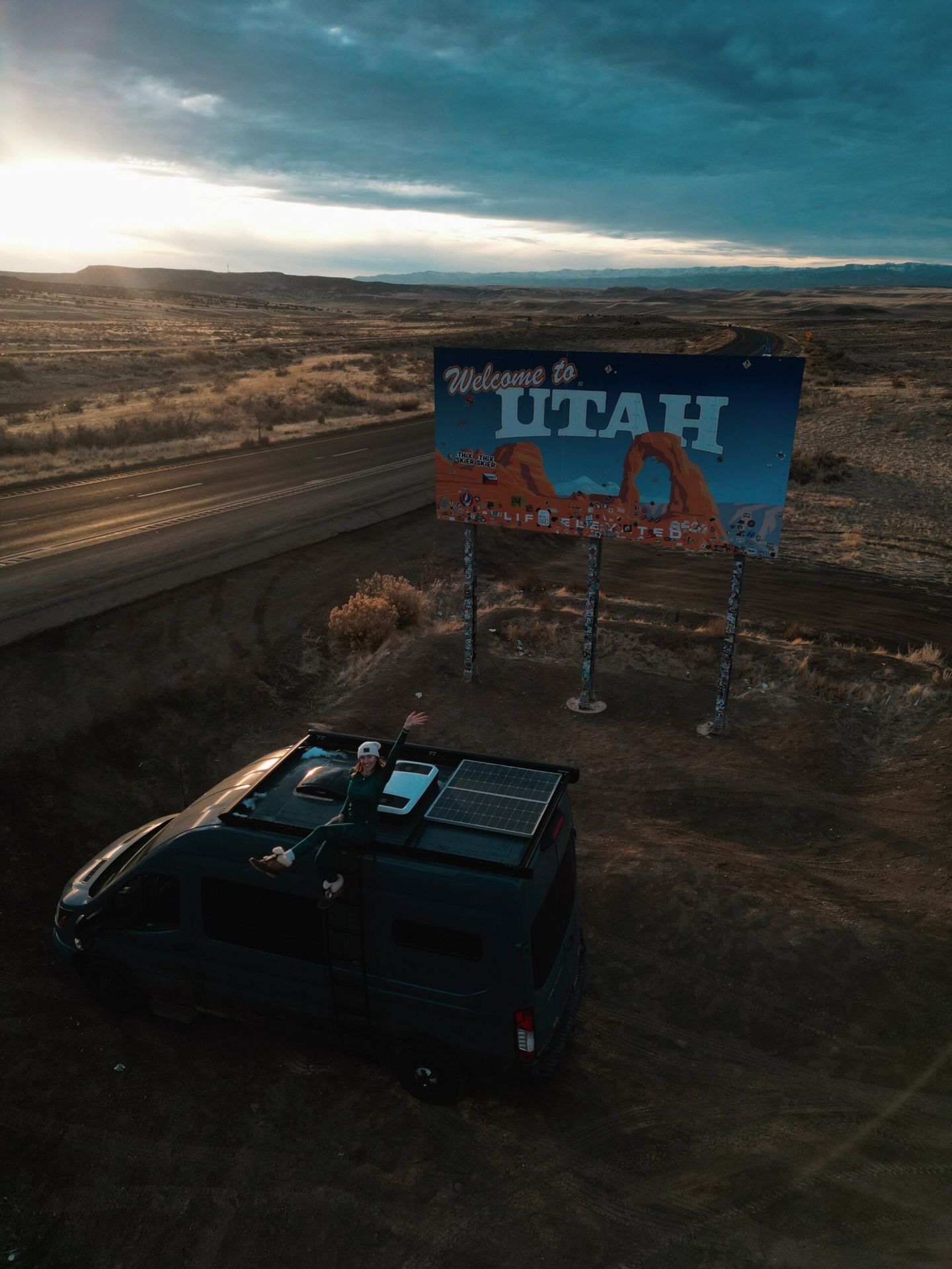 Allie Cheney and her van at the 'Welcome to Utah' sign.
