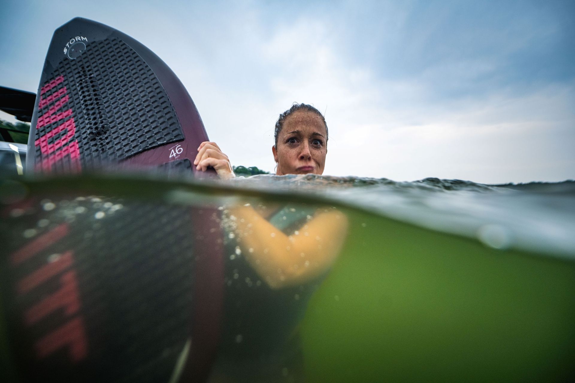 Young woman enjoying summer water sports at the lake with her favorite wakeboard.