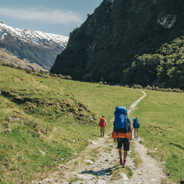 Backpackers traveling a well-worn trail through a mountain valley.