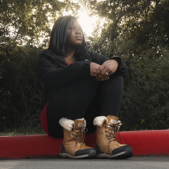 Afua Giles sitting on a curb with some Ugg Boots.