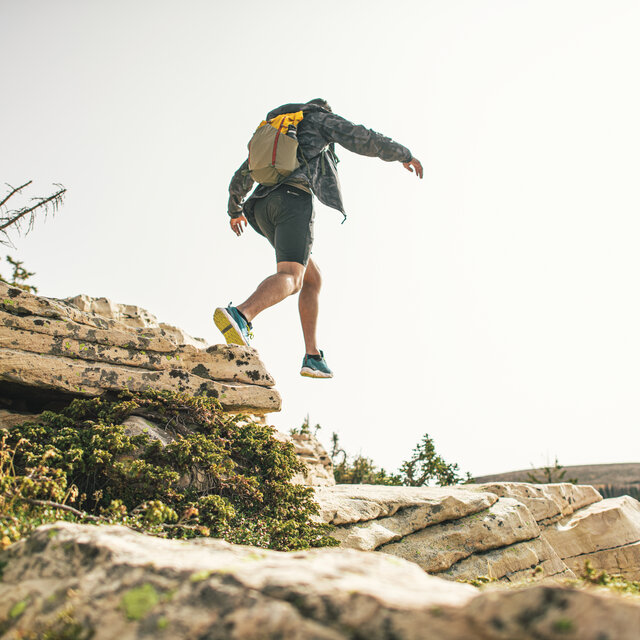 A hiker with a small hiking bag, navigating some rocks.