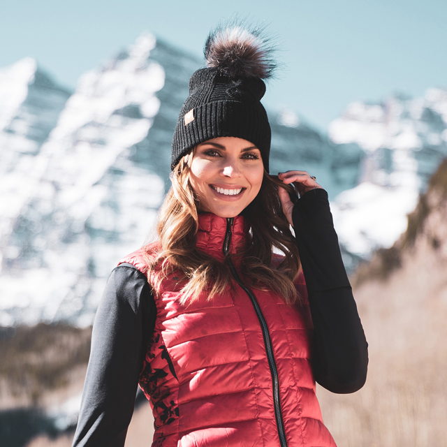A woman smiling with a puffy vest and midlayer.