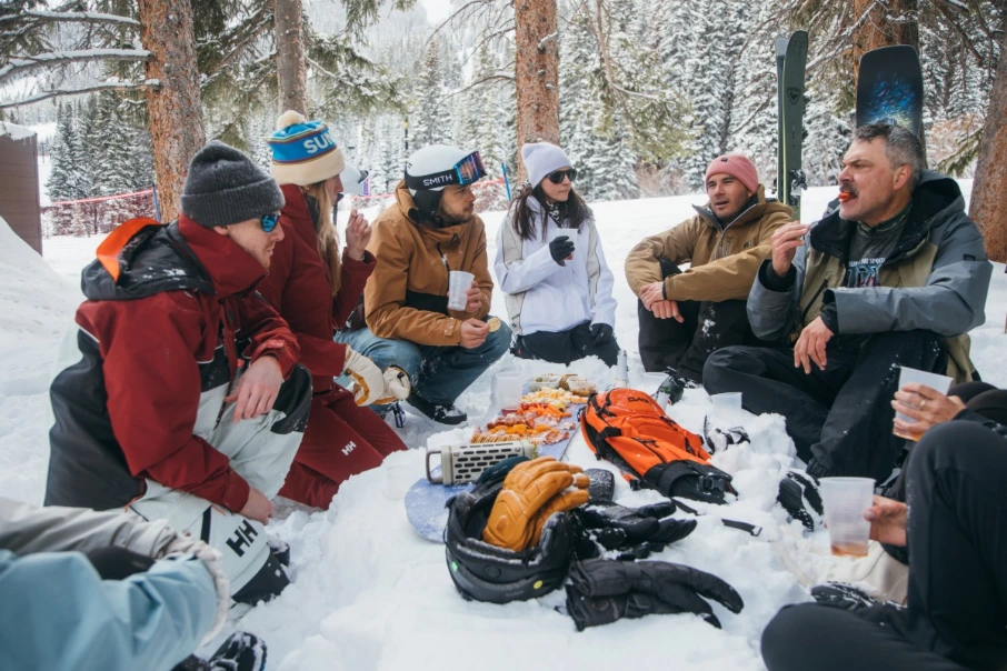 A group of skiers gathered around a pile of ski equipment